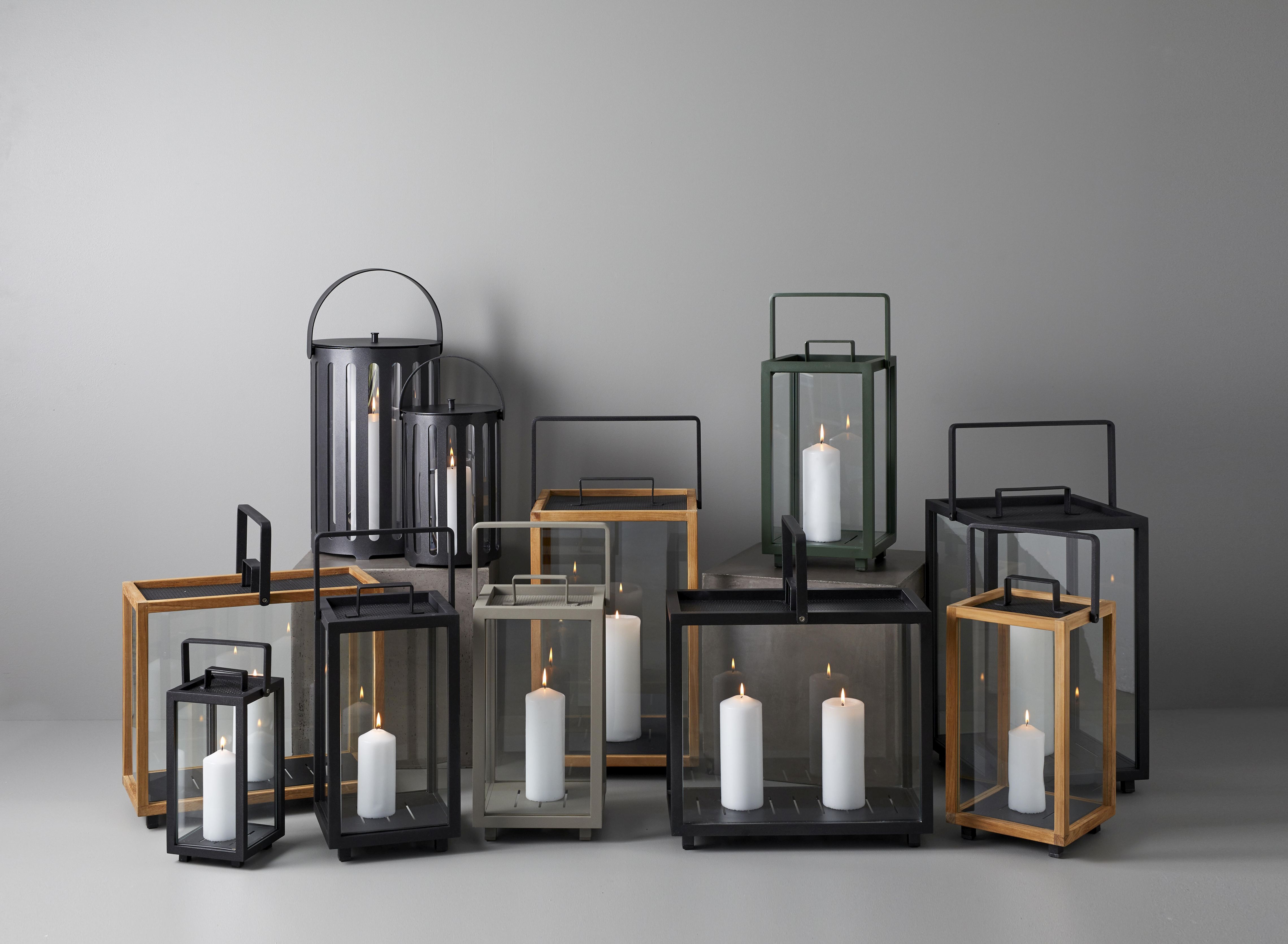 Eine Kollektion von Cane-Line Lighthouse Laternen aus Teakholz und Metall mit brennenden Kerzen.