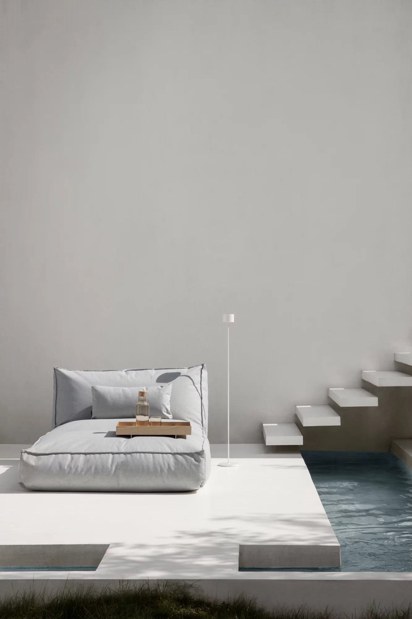 Blomus Stay Day Bed Outdoor in Grau neben Pool mit Getränken. Bequemes Tagesbett für Garten und Terrasse.