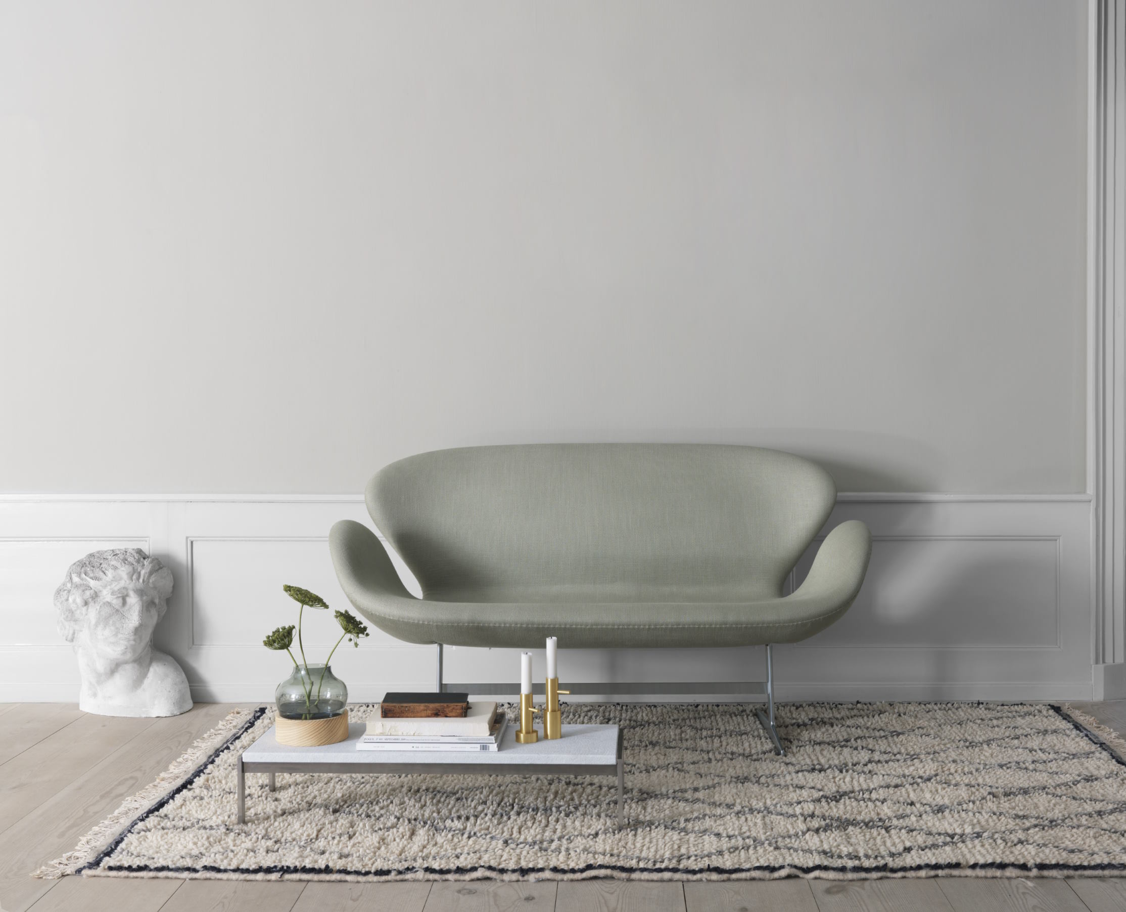 Helles Wohnzimmer mit modernem Schwansofa von Fritz Hansen in sanftem Grün.