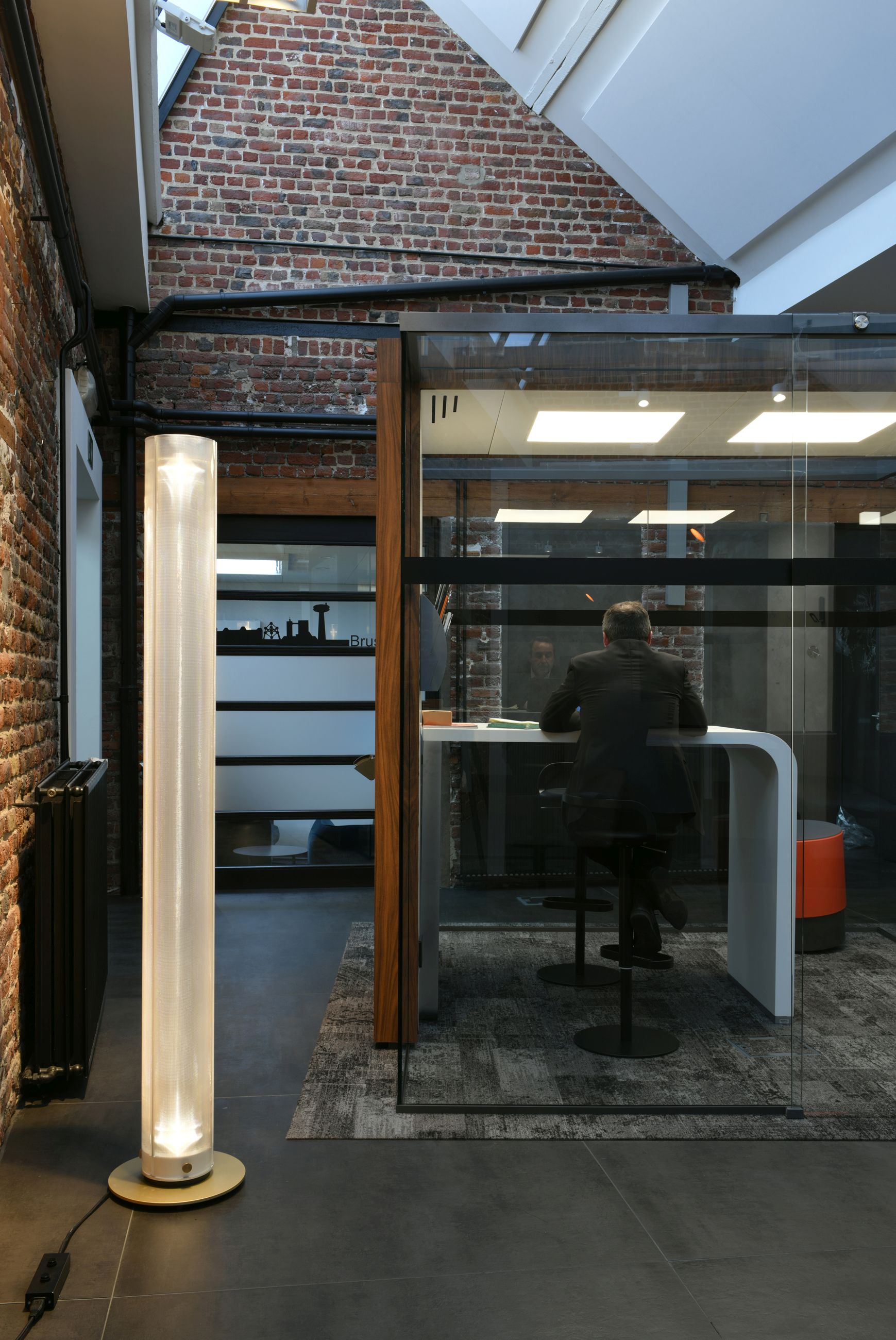 Twilight Stehleuchte von Belux im modernen Büro: Stehlampe mit sanftem Licht neben Arbeitsplatz mit Person.
