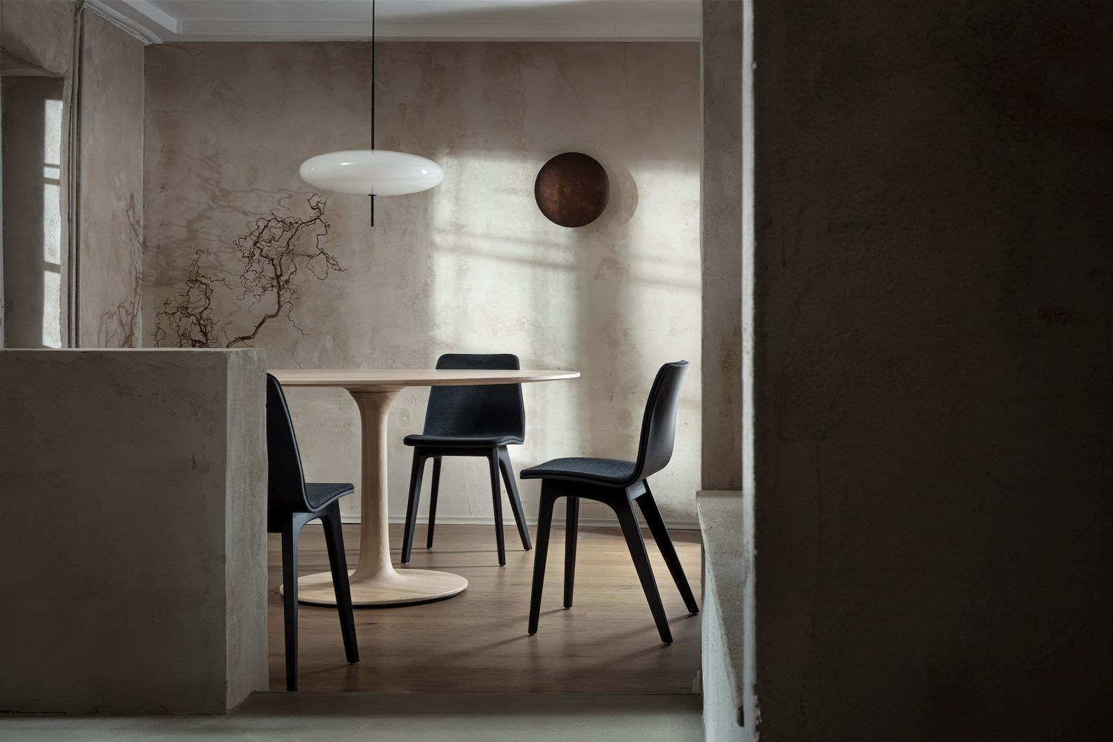Turntable Esstisch Zeitraum mit drei schwarzen Stühlen in modernem Esszimmer mit Pendelleuchte und Holzboden.