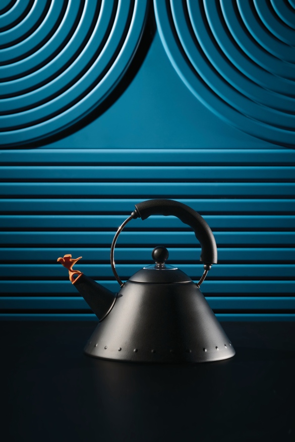Schwarzer Alessi Wasserkessel 9093 BB mit Vogelpfeife vor blauem Hintergrund für Teewasser.