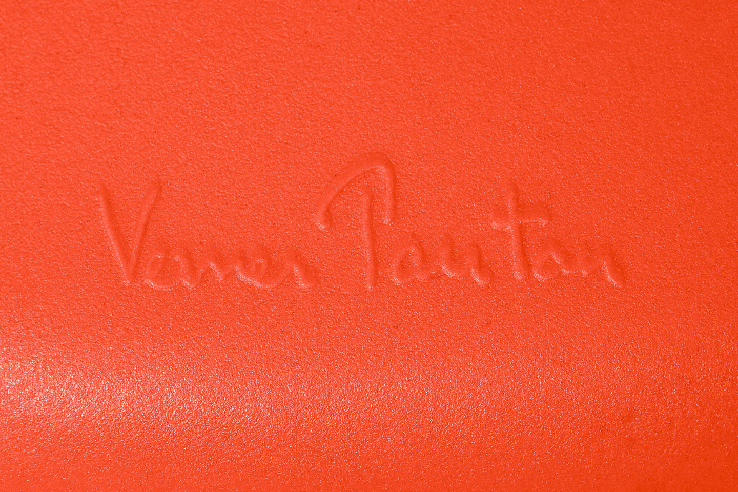 Detailaufnahme der Signatur "Verner Panton" auf einem orangefarbenen Panton Chair Classic Stuhl von Vitra.