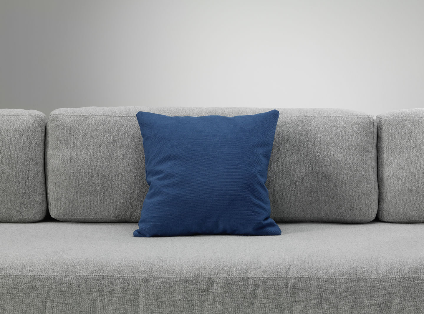 Blaues Vitra Kissen auf einem grauen Sofa, modernes Wohnaccessoire für stilvolles Wohnzimmerdesign.