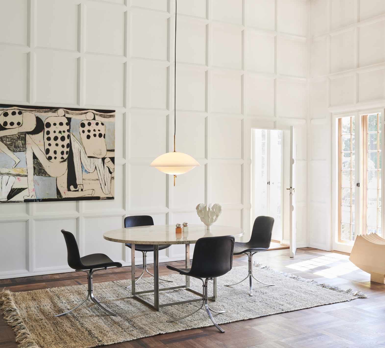 Esszimmer mit Fritz Hansen Clam Pendelleuchte 55 cm, die über einem runden Tisch hängt.