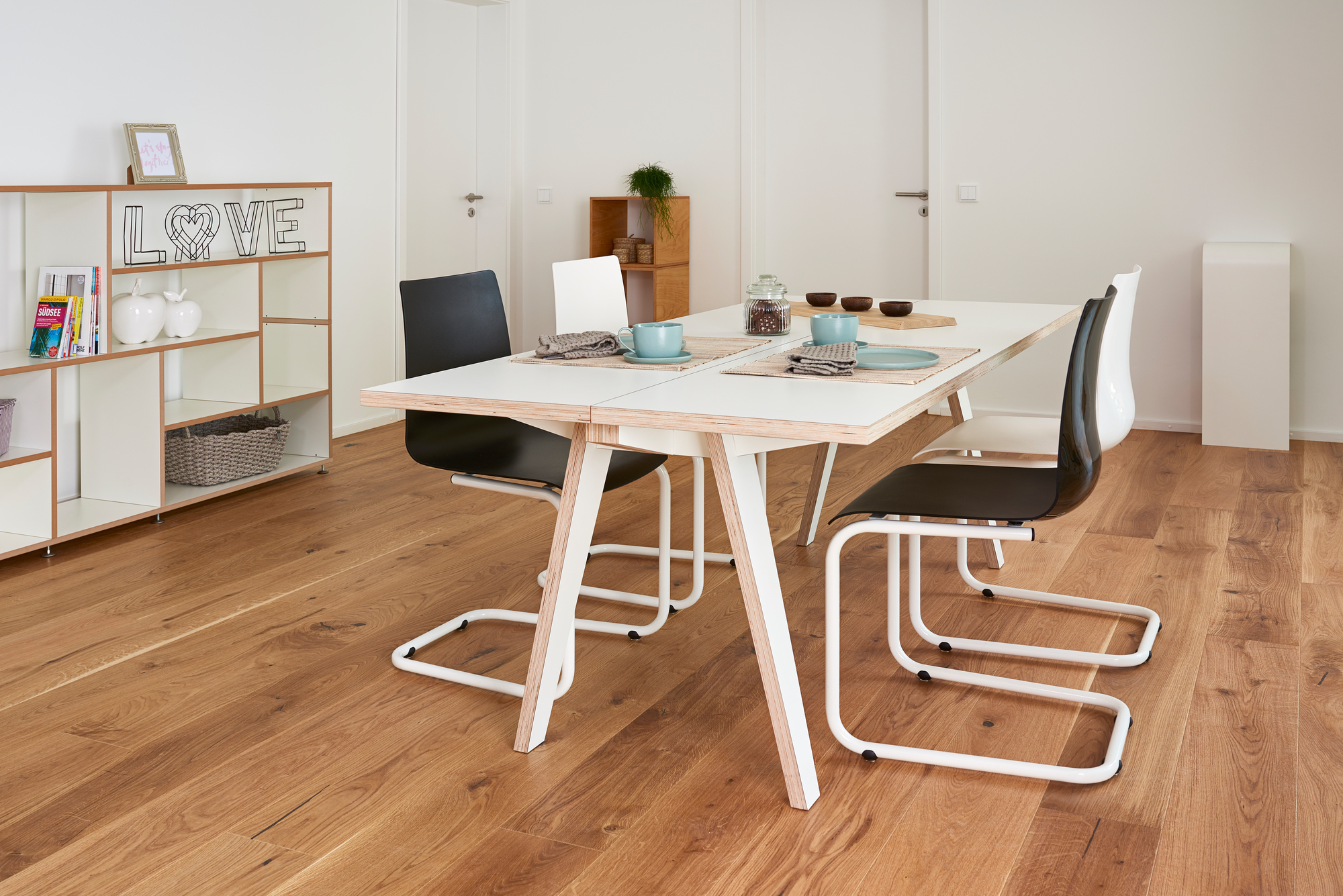 Heller Essbereich mit Tojo Steck Tisch aus Holz und weißen Beinen, gedeckt mit Geschirr.