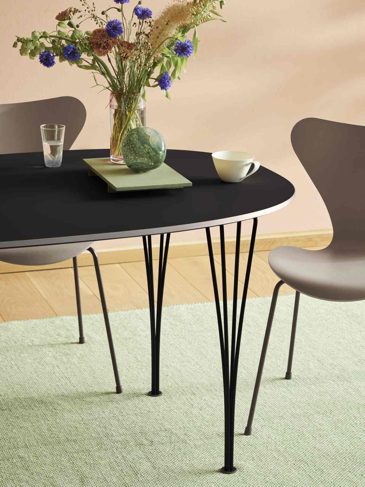 Schwarzer Esstisch Super Elliptisch von Fritz Hansen mit filigranem Stahlgestell und Dekoration, geeignet für modernes Wohnambiente.