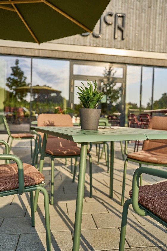 Weishäupl Vapio Tisch Outdoor mit grüner Tischplatte und Stühlen auf einer Terrasse.