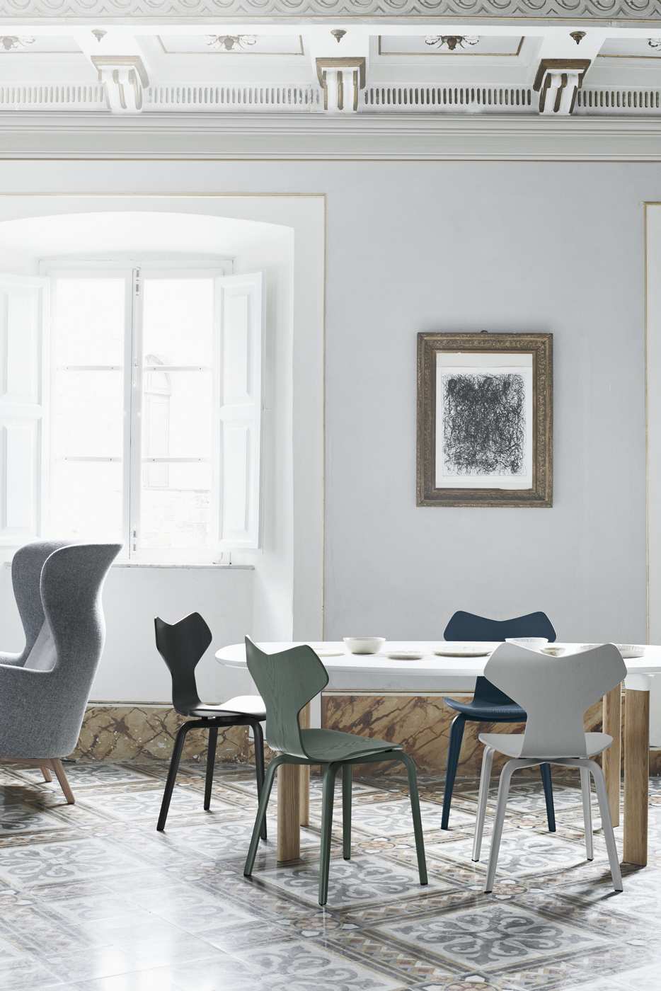 Esszimmer mit ovalem Analog Tisch von Fritz Hansen und farbigen Stühlen auf gemustertem Fliesenboden.
