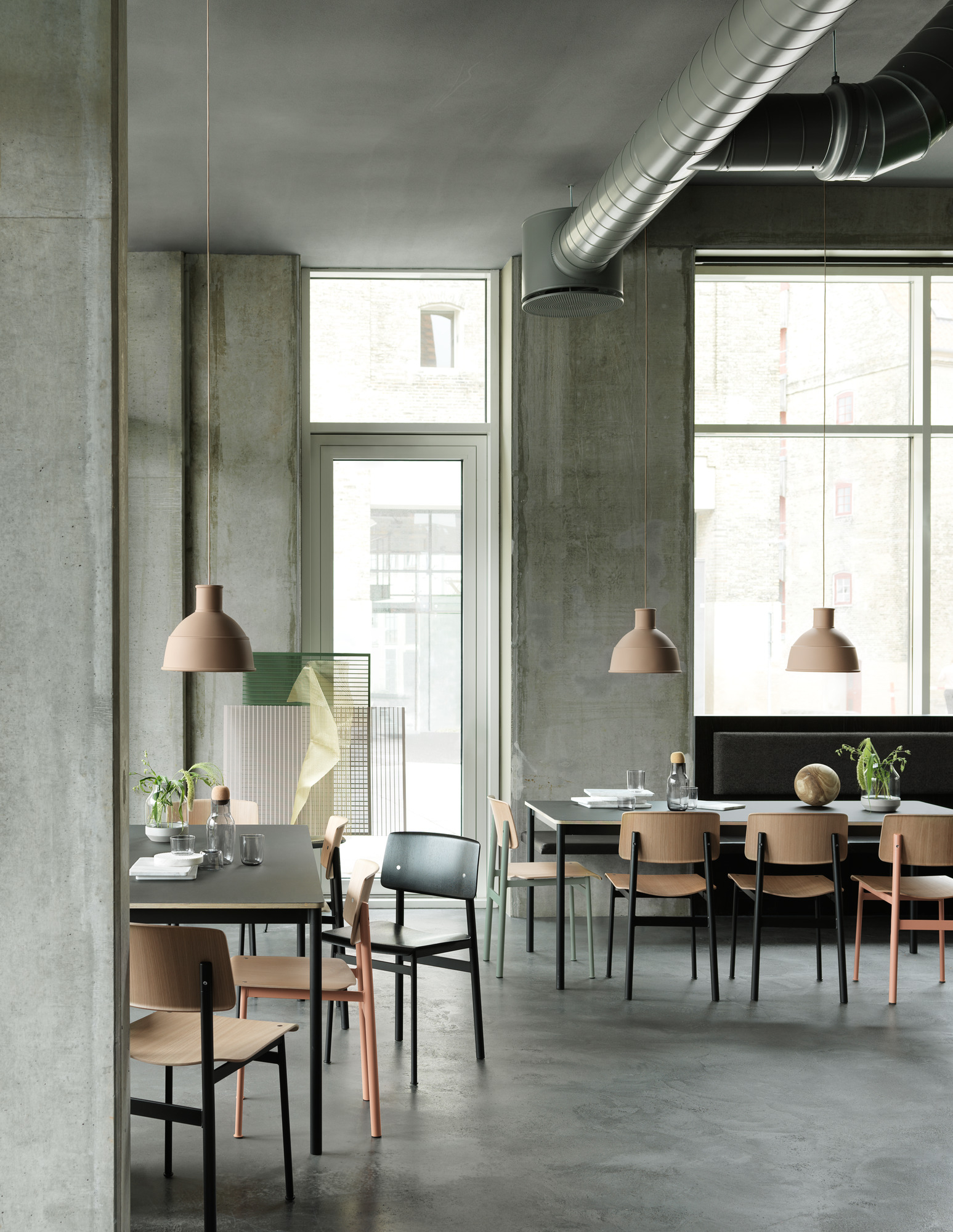 Innenaufnahme eines modernen Restaurants mit mehreren Muuto Base Table Round Tischen und Stühlen.