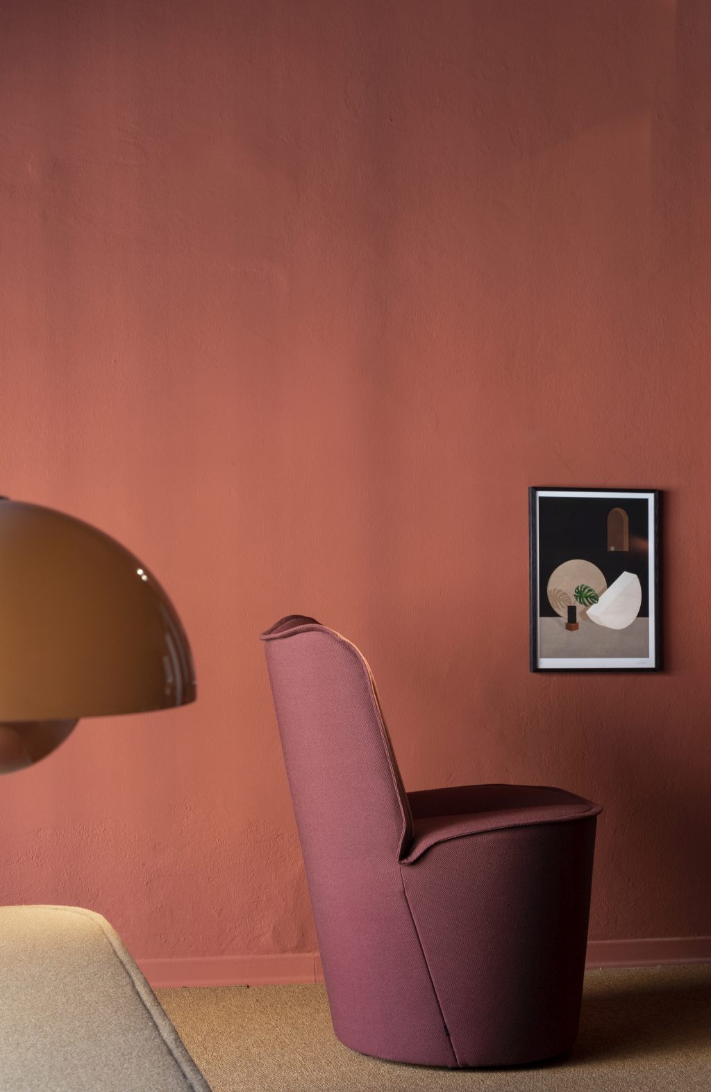 Nenou Sessel von Cor, moderner Polstersessel in Pflaume vor einer Wand mit Kunstwerk.