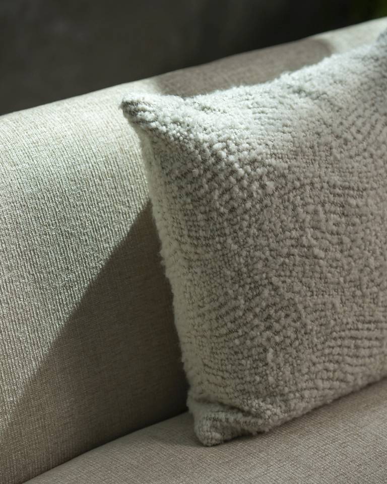 Nahaufnahme des Ethnicraft Wave Cushion Kissens (60x40 cm) in Off-White auf einem Sofa, Texturdetails sichtbar.