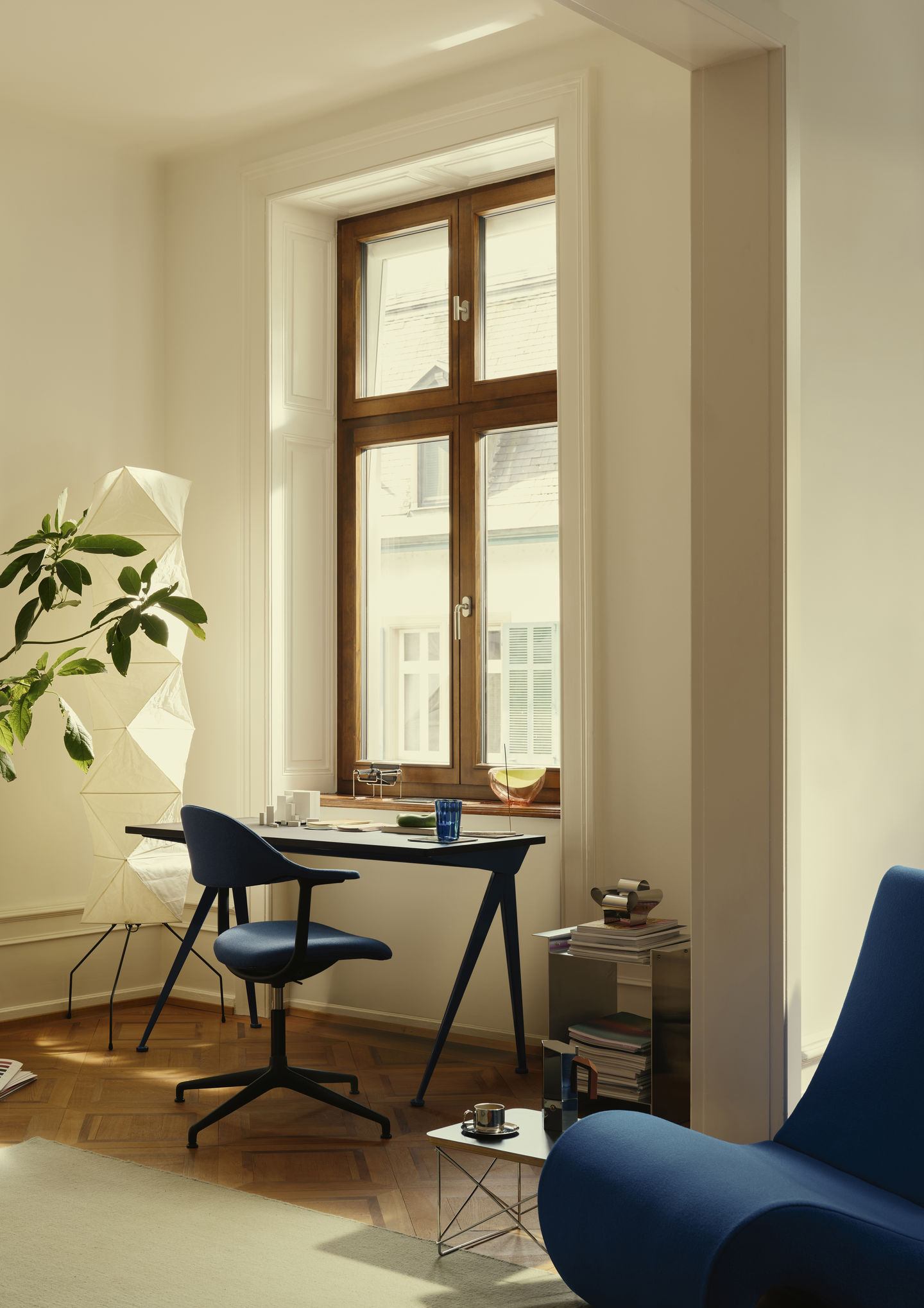 Mynt Bürodrehstuhl von Vitra mit blauer Sitzschale und Rückenlehne am Schreibtisch in hellem Arbeitszimmer.