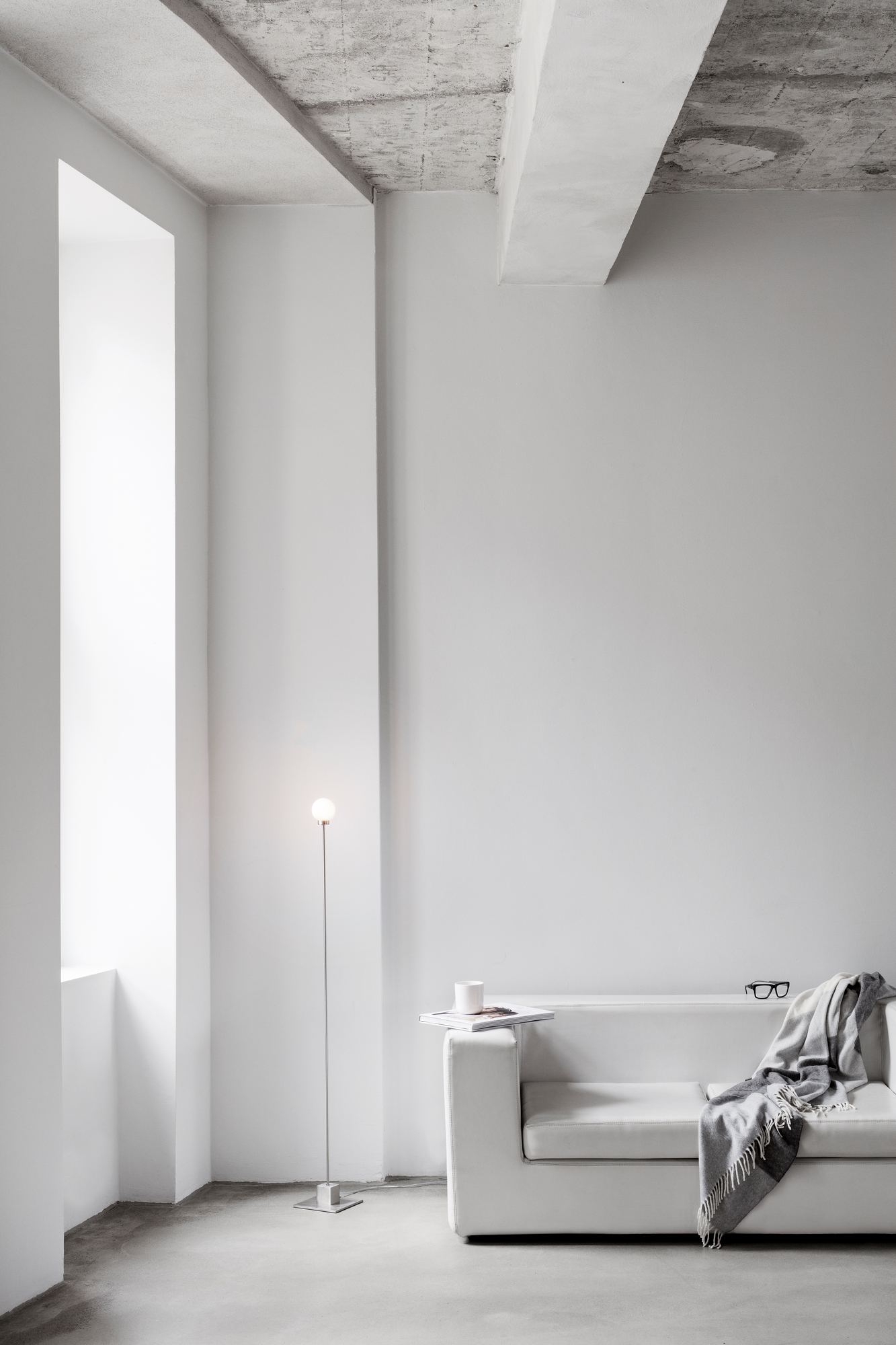 Minimalistische, weiße Inneneinrichtung mit Snowball LED Stehleuchte von Northern, Sofa, Decke und Betonboden.