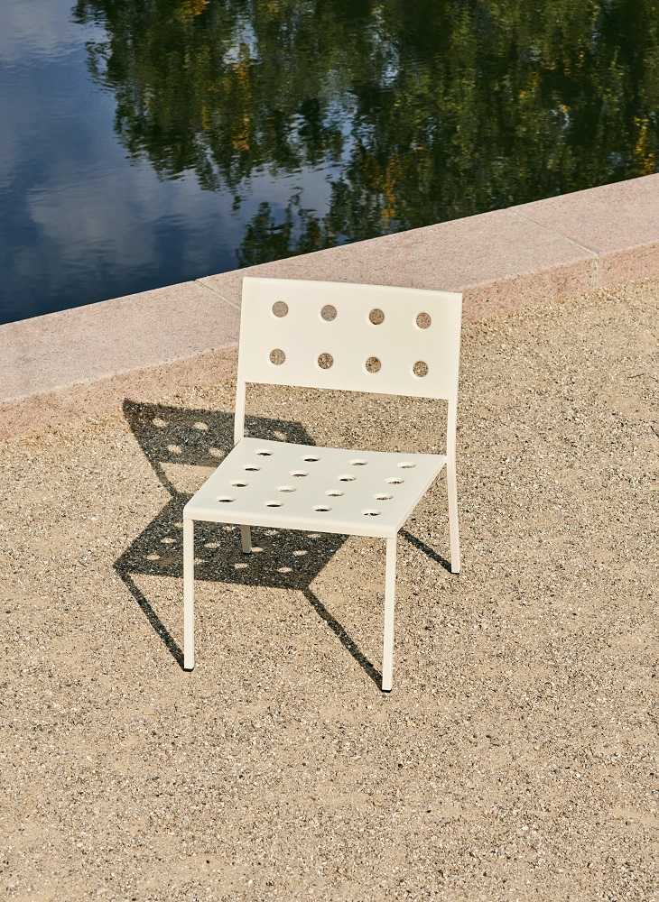 Weißer Hay Balcony Outdoor Lounge Chair Stuhl mit Lochmuster auf Kiesboden, modernes Gartenmöbel Design.
