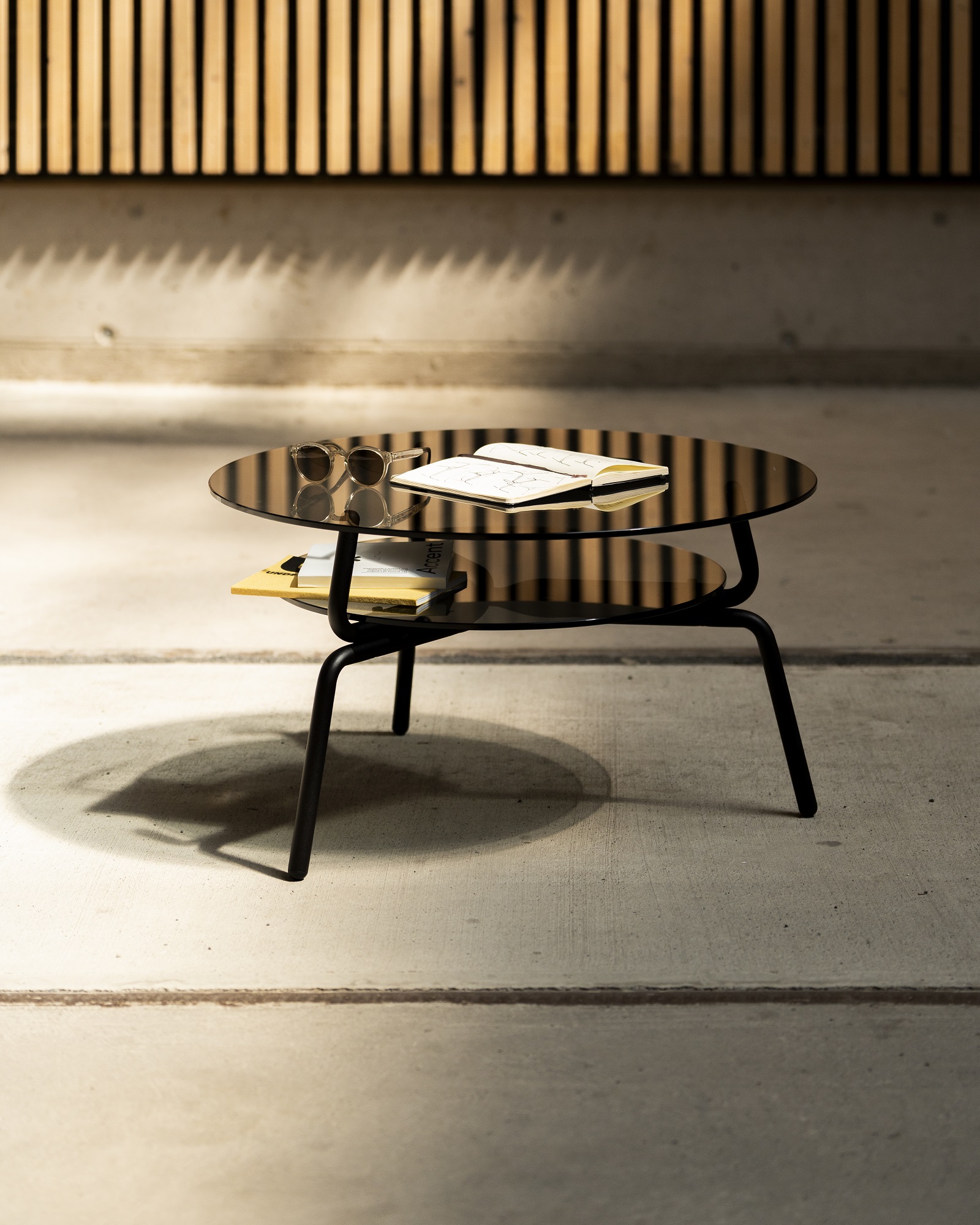 Lej Couchtisch Transparent Mox mit runder Glasplatte und schwarzem Metallgestell, mit Ablagefläche.