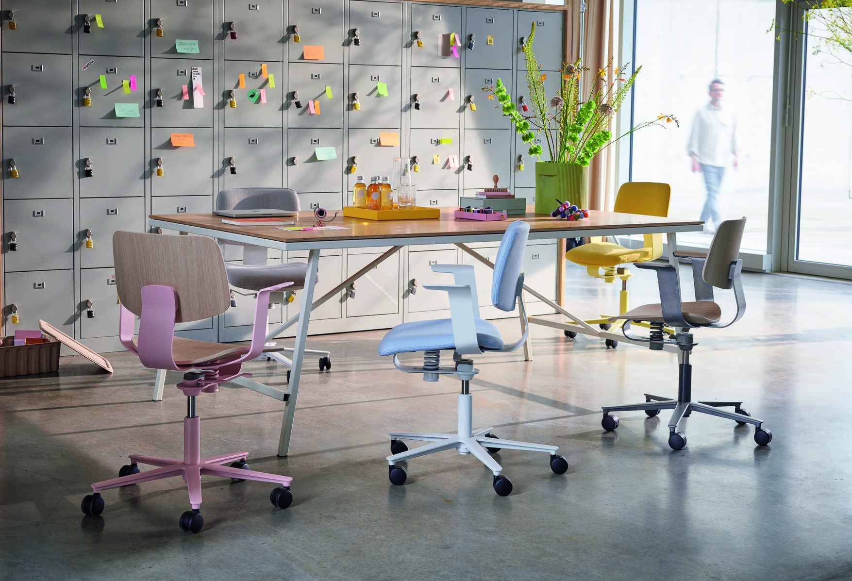 Mehrere 228 WiChair Drehstühle von Wilkhahn in verschiedenen Farben um einen Tisch in einem modernen Büro.