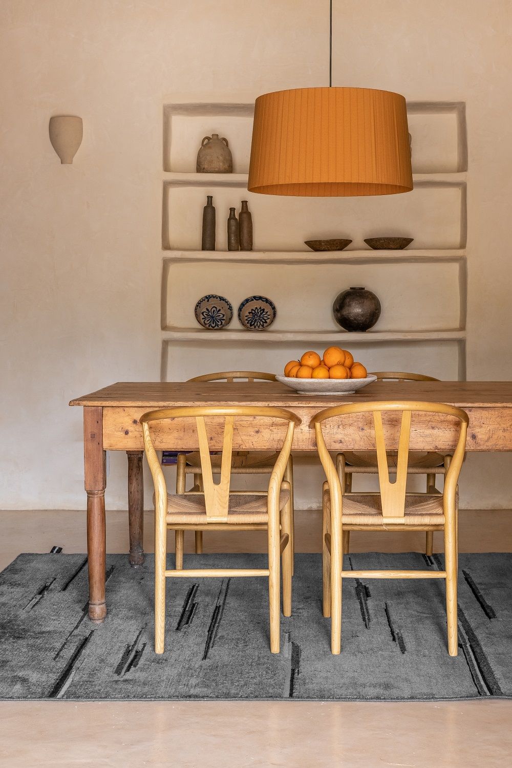 Colorado Teppich von Nanimarquina in grau unter einem Holzesstisch mit Stühlen und Obstschale.