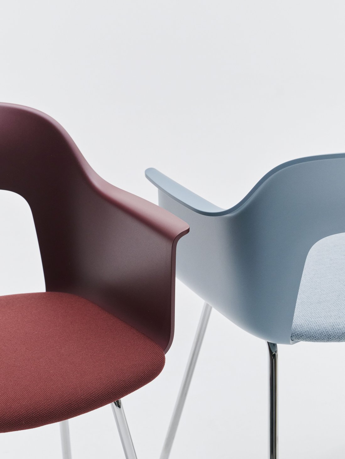 Nahaufnahme von zwei Hay Armlehnstühlen, Modell Layout Armchair 213, in Rot und Blau. Moderne Sitzmöbel mit Chromgestell.