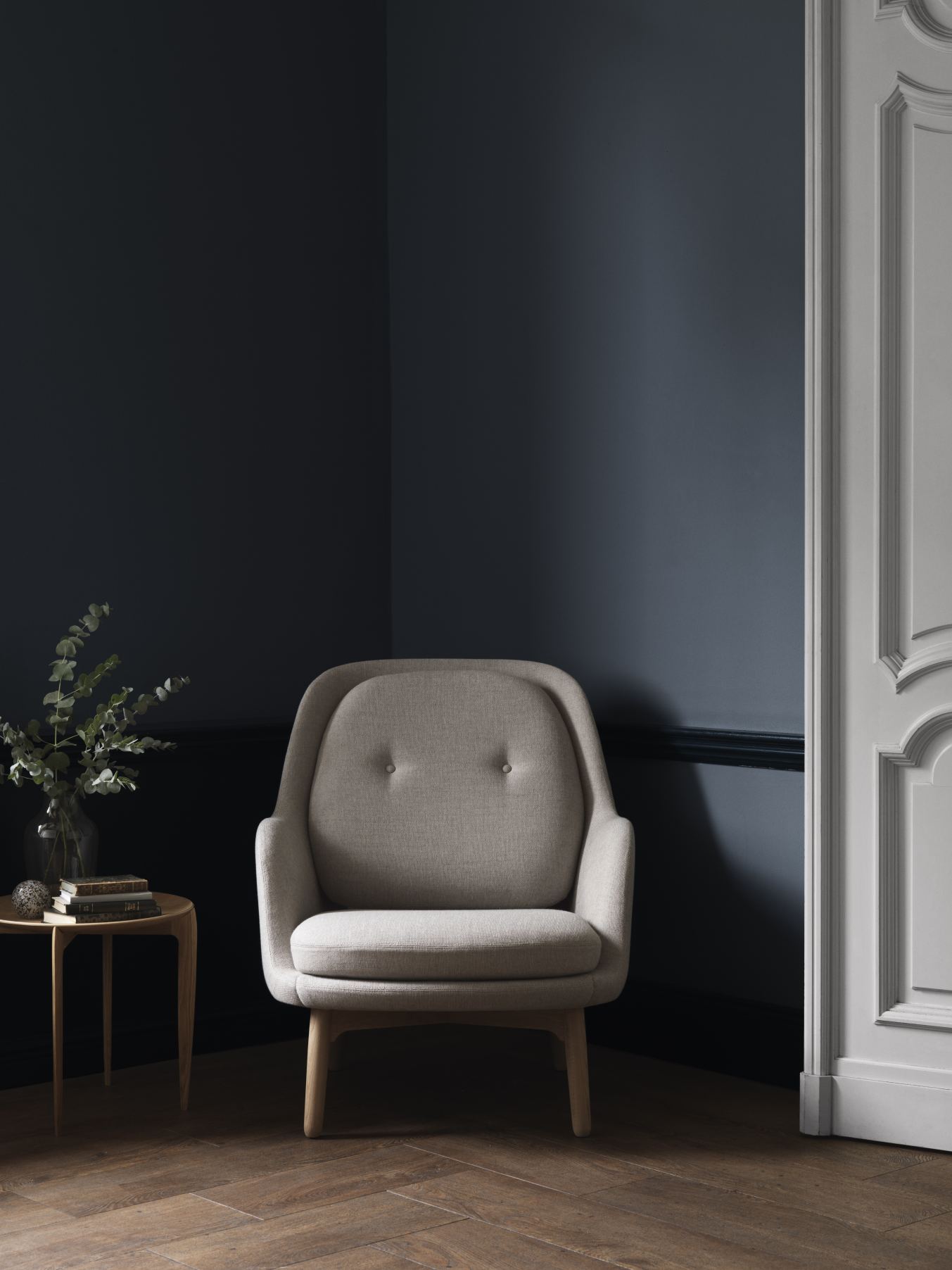 Beiger Fri Sessel von Fritz Hansen im Interieur mit dunkler Wand und Holzboden.