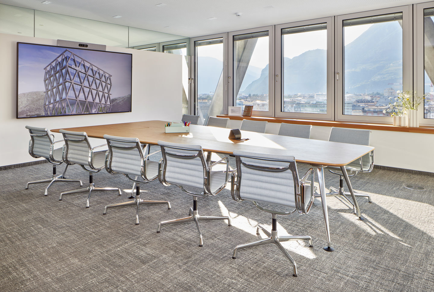 Konferenzraum mit langem Tisch und mehreren Aluminium Chair EA 104 Stühlen von Vitra in Grau.