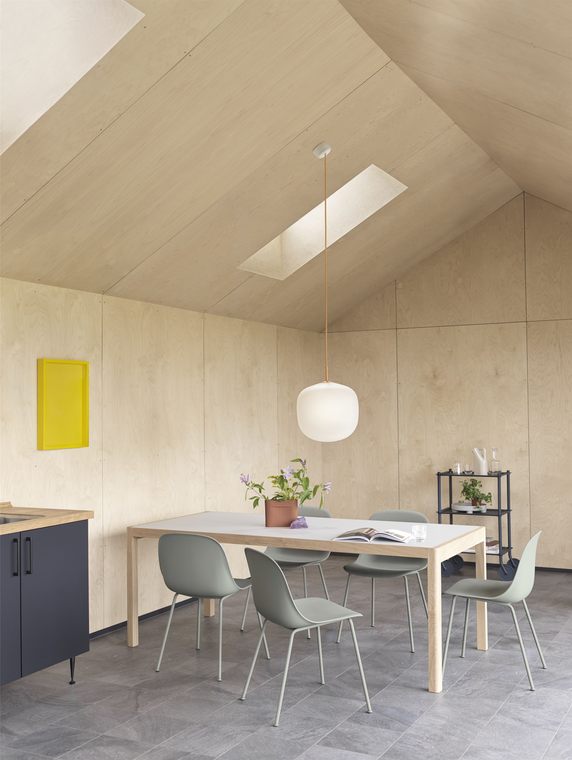 Helle Küche mit Esstisch und vier grauen Muuto Fiber Side Chairs mit Stahlrohrgestell.