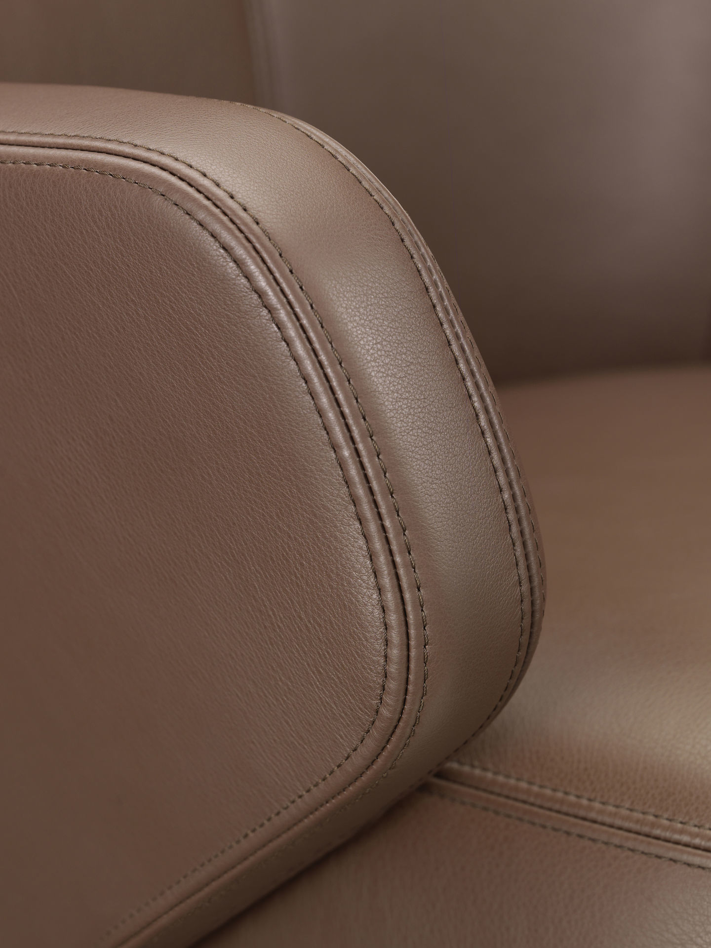 Detailaufnahme des braunen Lederbezugs vom Vitra Grand Conference Lowback Konferenzstuhl mit feinen Ziernähten.