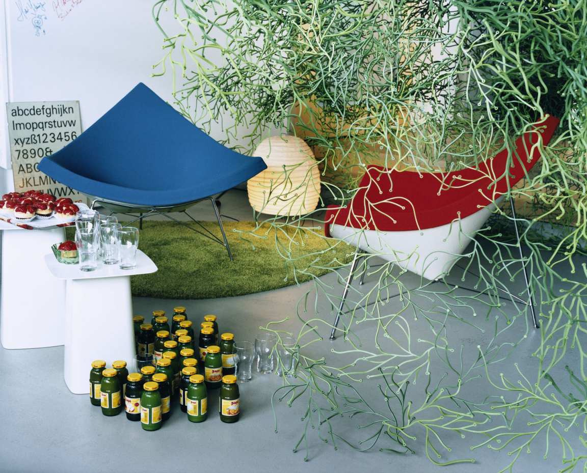 Blauer und roter Vitra Coconut Chair im modernen Wohnzimmer mit Getränken und Dekoration.