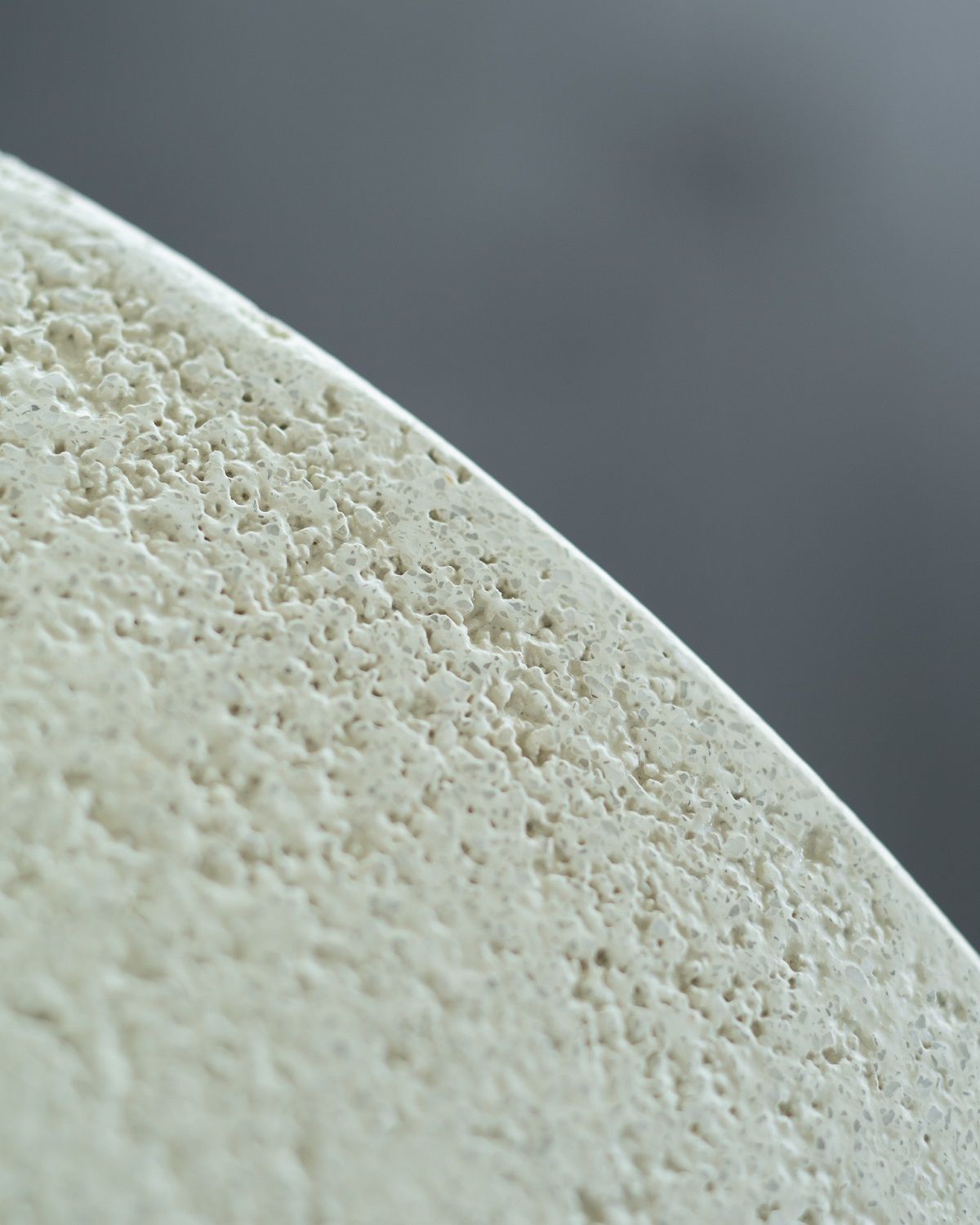 Detailaufnahme der Microcement-Oberfläche vom Ethnicraft Elements Couchtisch in Off White, runder Tisch mit einzigartiger Textur.