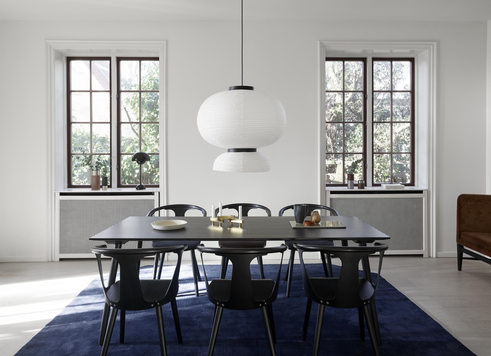 Formakami JH5 Hängeleuchte von AndTradition über Esstisch mit Stühlen und blauem Teppich.