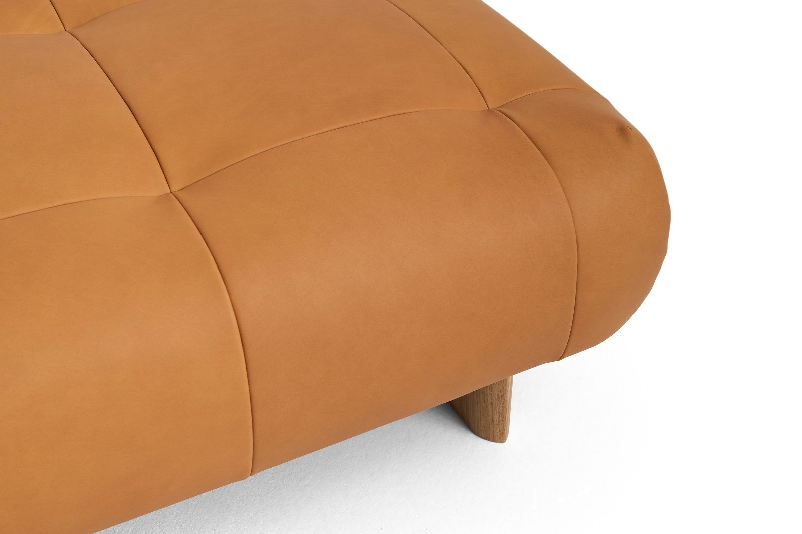 Detailaufnahme des Quilton Lift Ottoman Hockers von Hay in braunem Leder mit Holzfüßen.
