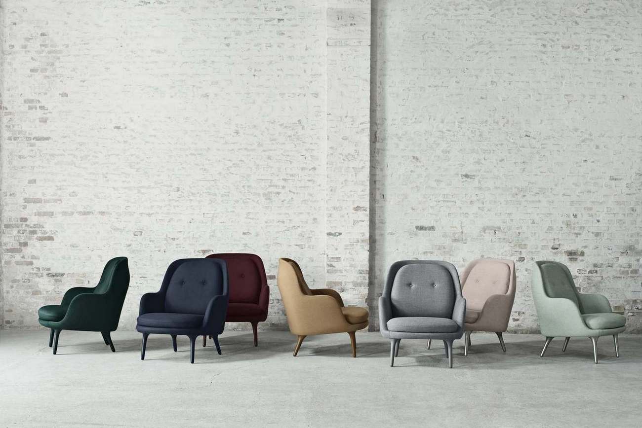 Fritz Hansen Fri Sessel in verschiedenen Farben vor einer weißen Backsteinwand, modernes Möbeldesign.