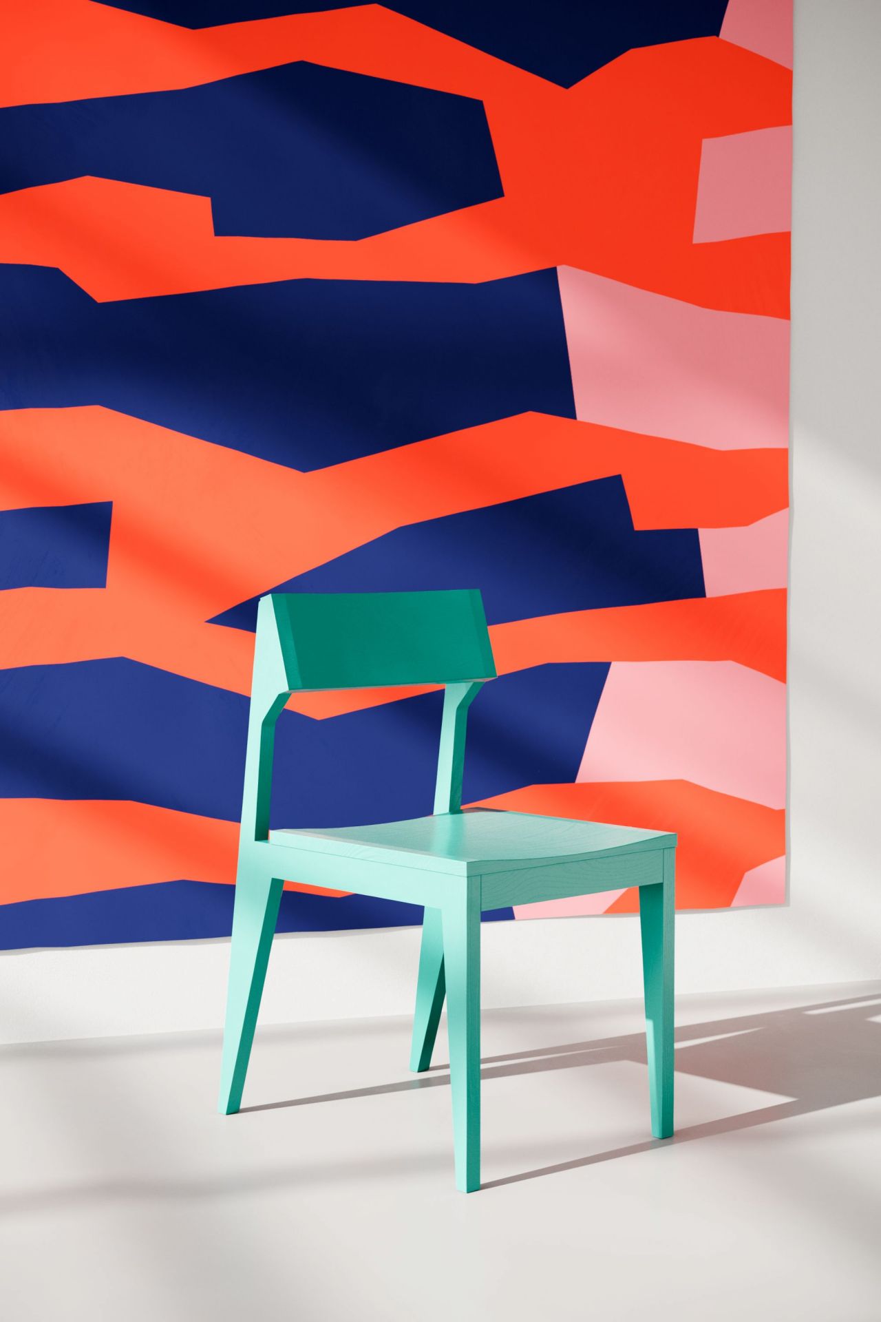 Mintgrüner Holzstuhl vor abstrakter Wandkunst, modernes Möbeldesign für Wohnzimmer und Esszimmer.