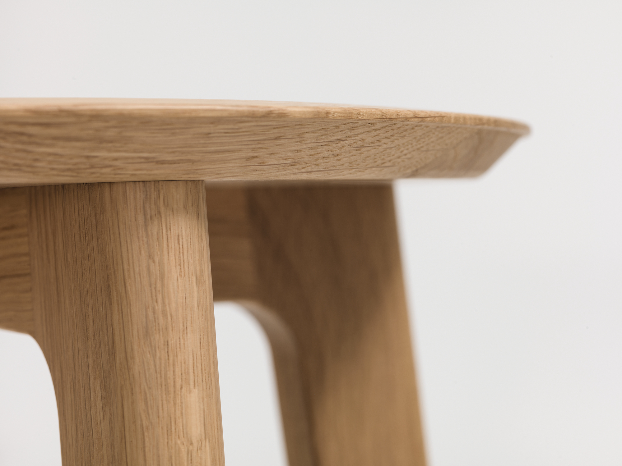 Detailaufnahme eines modernen Barhockers aus hellem Holz, Fokus auf Sitzfläche und Beine.