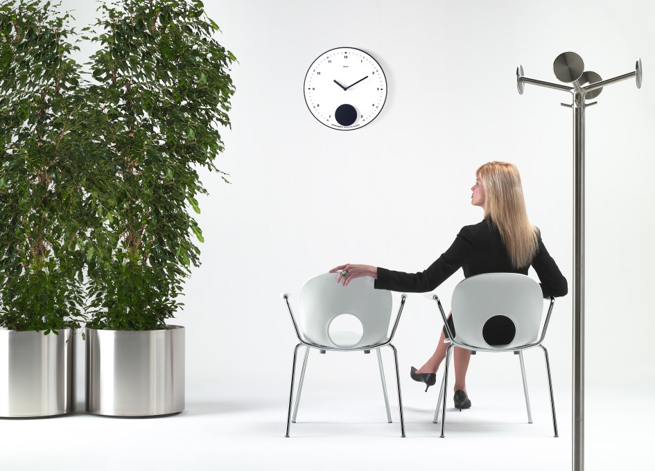 Nox Flora Blumentopf auf Rollen von Rexite neben Frau auf Stuhl, Zimmerpflanze im Metalltopf.