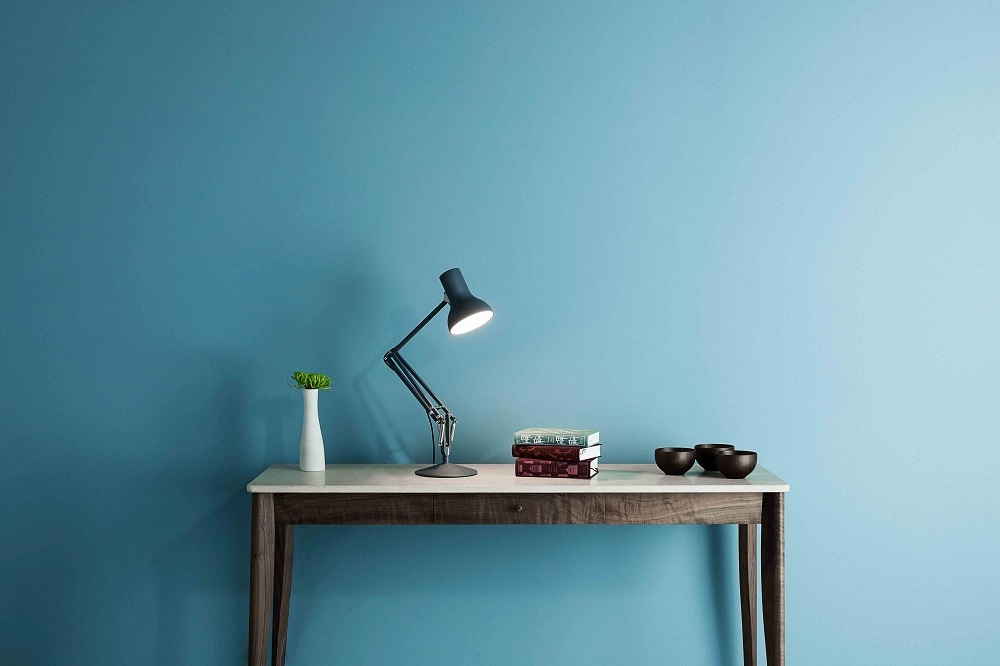 Type 75 Mini Anglepoise Tischleuchte in Alpinweiß auf Schreibtisch mit Büchern und Dekoration.