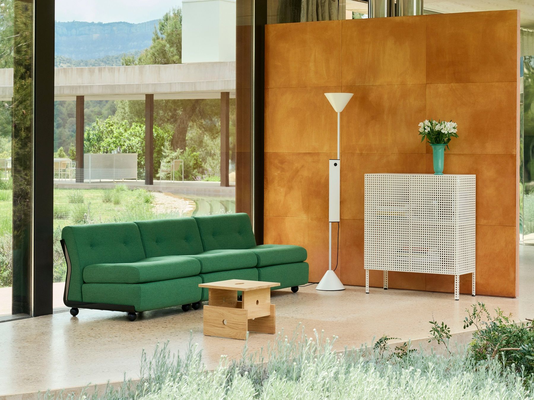 Helle, moderne Inneneinrichtung mit Hay Stehleuchte, grünem Sofa, Holztisch und weißem Schrank.