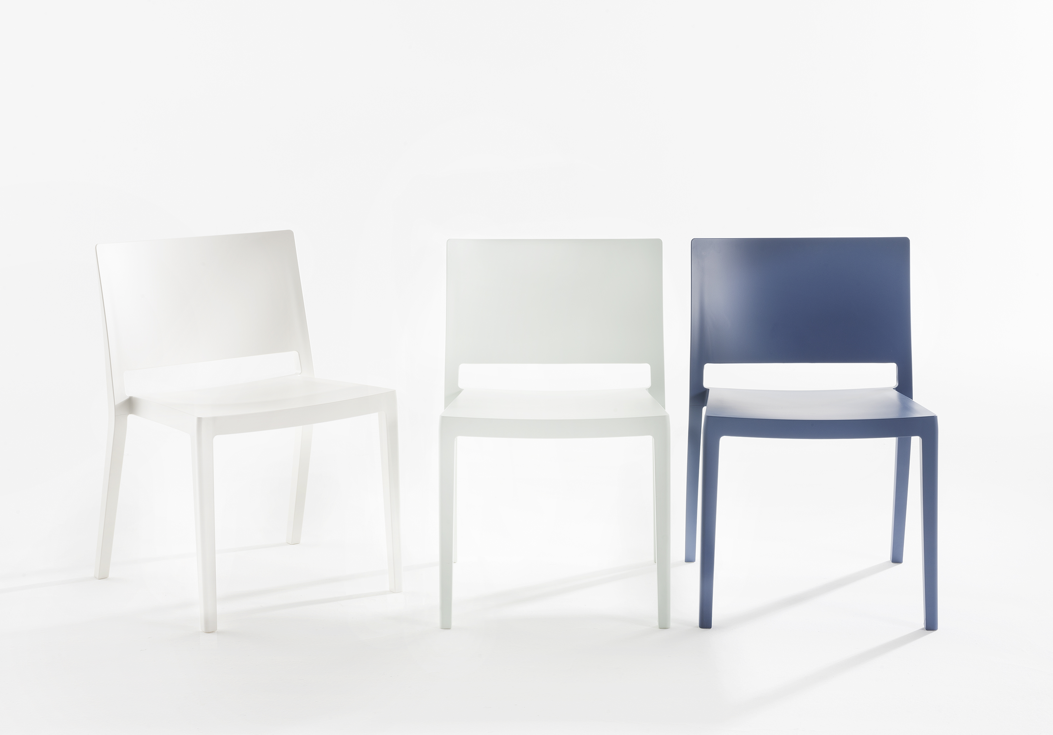 Drei Stühle: Zwei weiße Kartell Stühle, ein blauer Stuhl. Moderne Sitzmöbel für Esszimmer oder Küche.