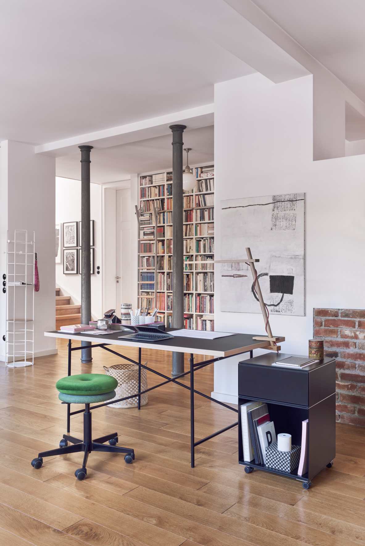 Eiermann Tisch mit schwarzem Gestell und Arbeitsplatte in modernem Büro mit Bücherregal.