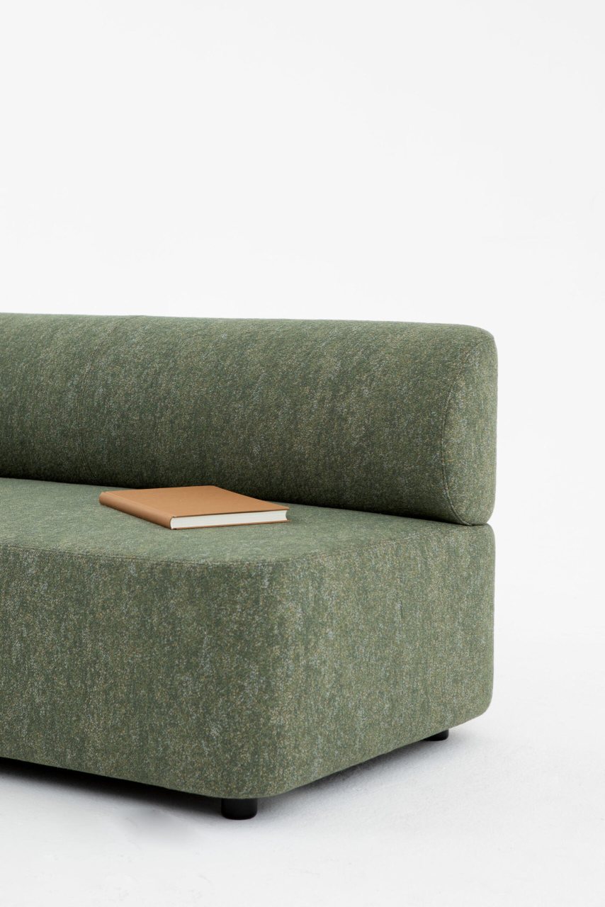 Mezza Sitzelement mit Rückenlehne von Cascando, modernes grünes Sofa mit Buch im Detail.