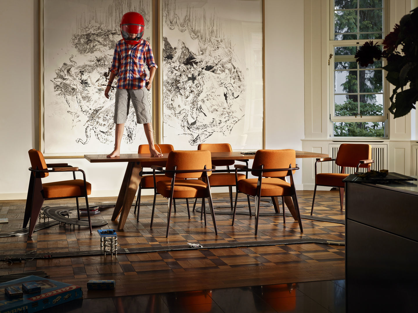 Orangefarbener Fauteuil Direction Sessel von Vitra in einem Wohnzimmer mit Kind auf dem Tisch.