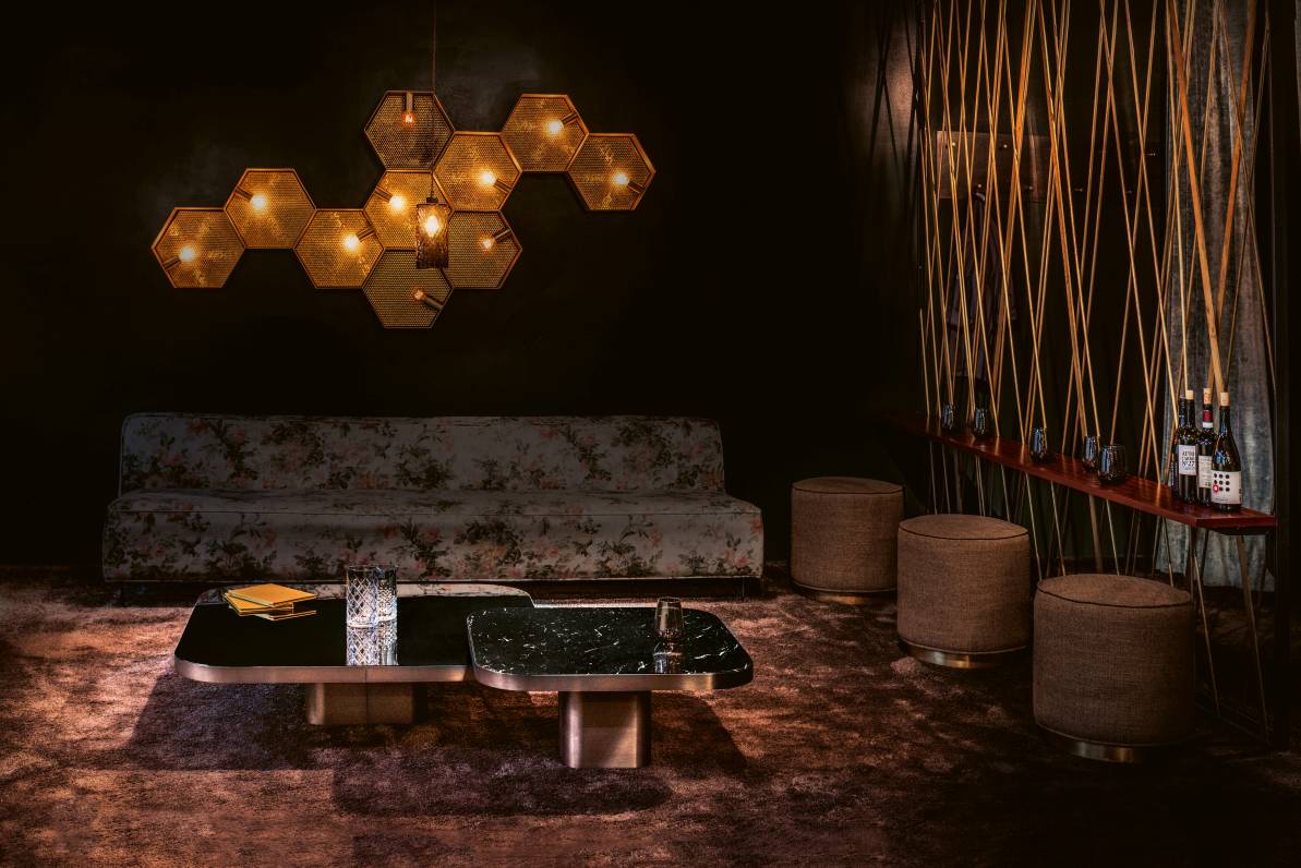 Elegantes Wohnzimmer mit ClassiCon Bow Coffee Table, floralem Sofa, Hockern und dekorativer Beleuchtung.