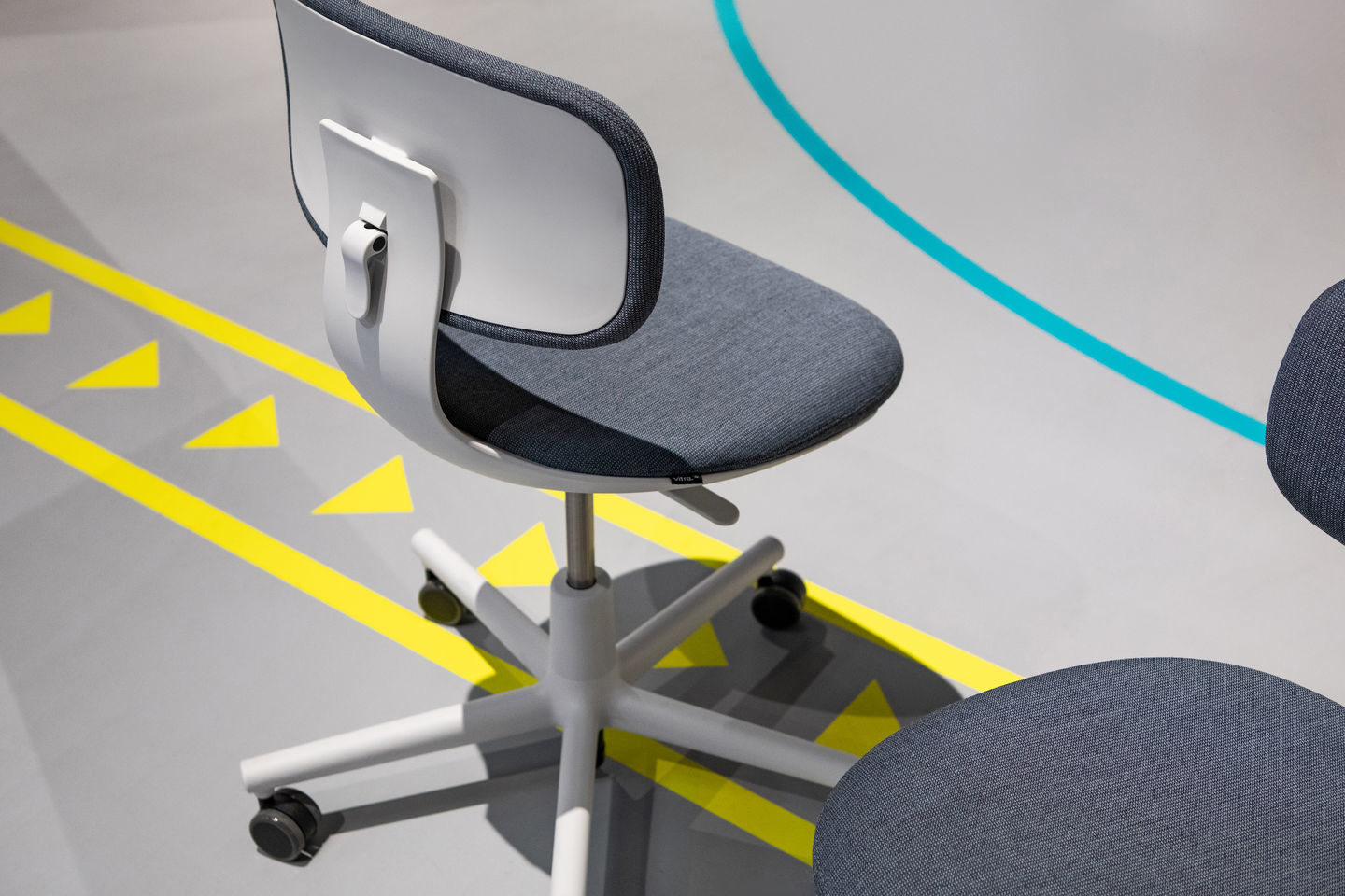 Nahaufnahme des Vitra Rookie Bürodrehstuhls mit grauem Stoffbezug und weißem Gestell, ideal für moderne Arbeitsplätze.