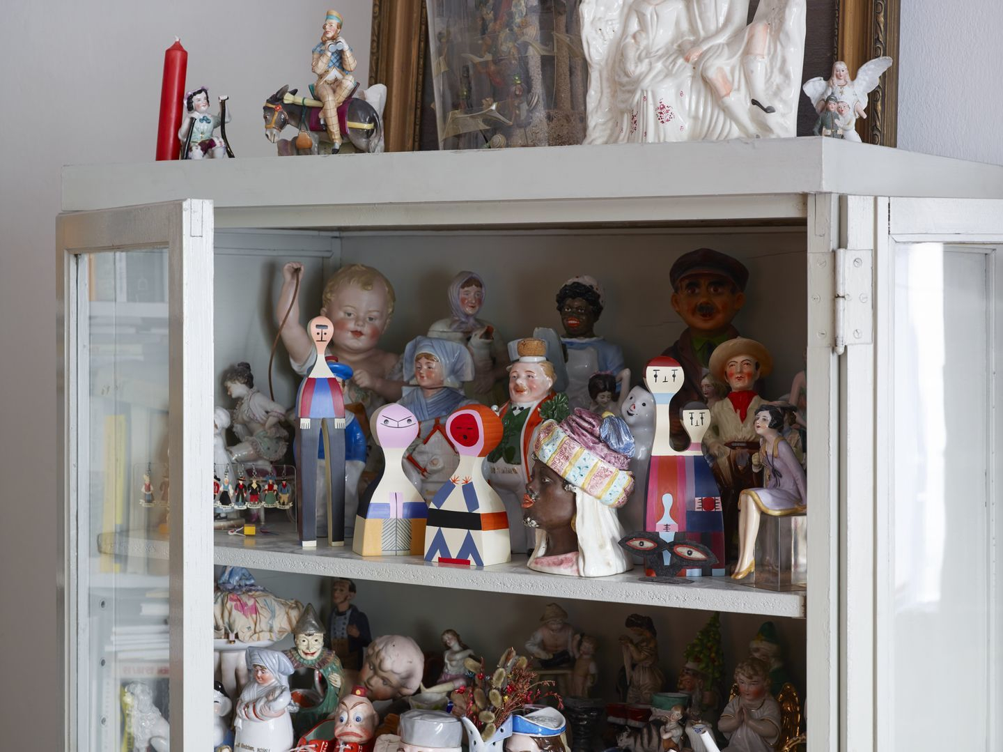 Regal mit Vintage-Puppen und Holzfiguren, darunter eine Vitra Wooden Doll, Sammlerstücke und dekorative Figuren.