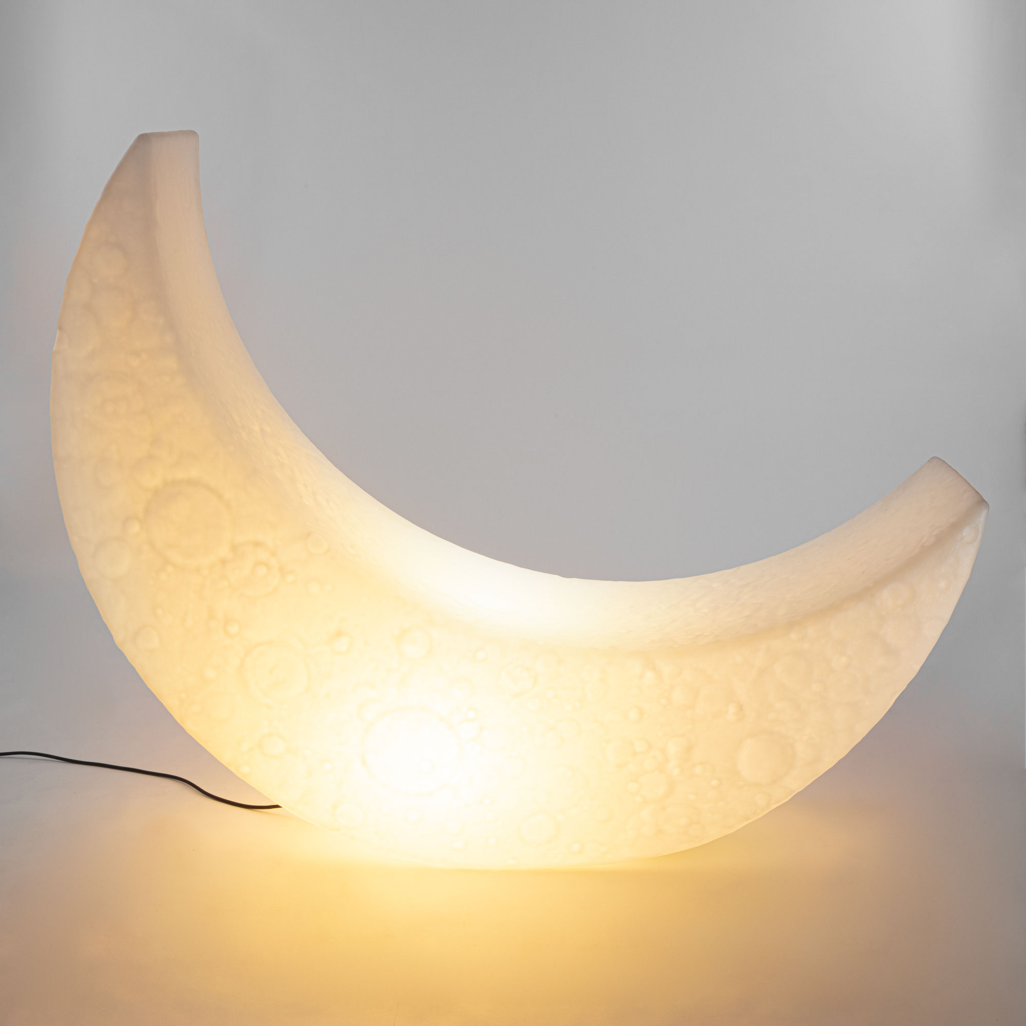 Nahaufnahme der Seletti My Moon Lampe, die ein warmes, stimmungsvolles Licht ausstrahlt und Mondkrater-Details zeigt.