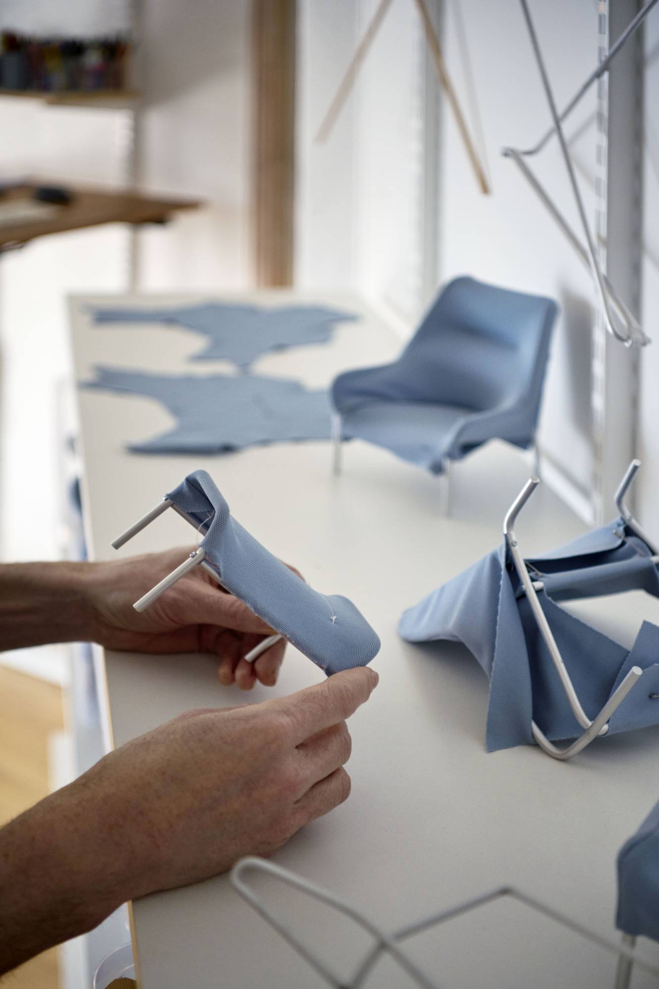 Nahaufnahme: Hände montieren blauen Hay Sessel, Möbeldesign, minimalistischer Lounge Chair, skandinavisches Design.
