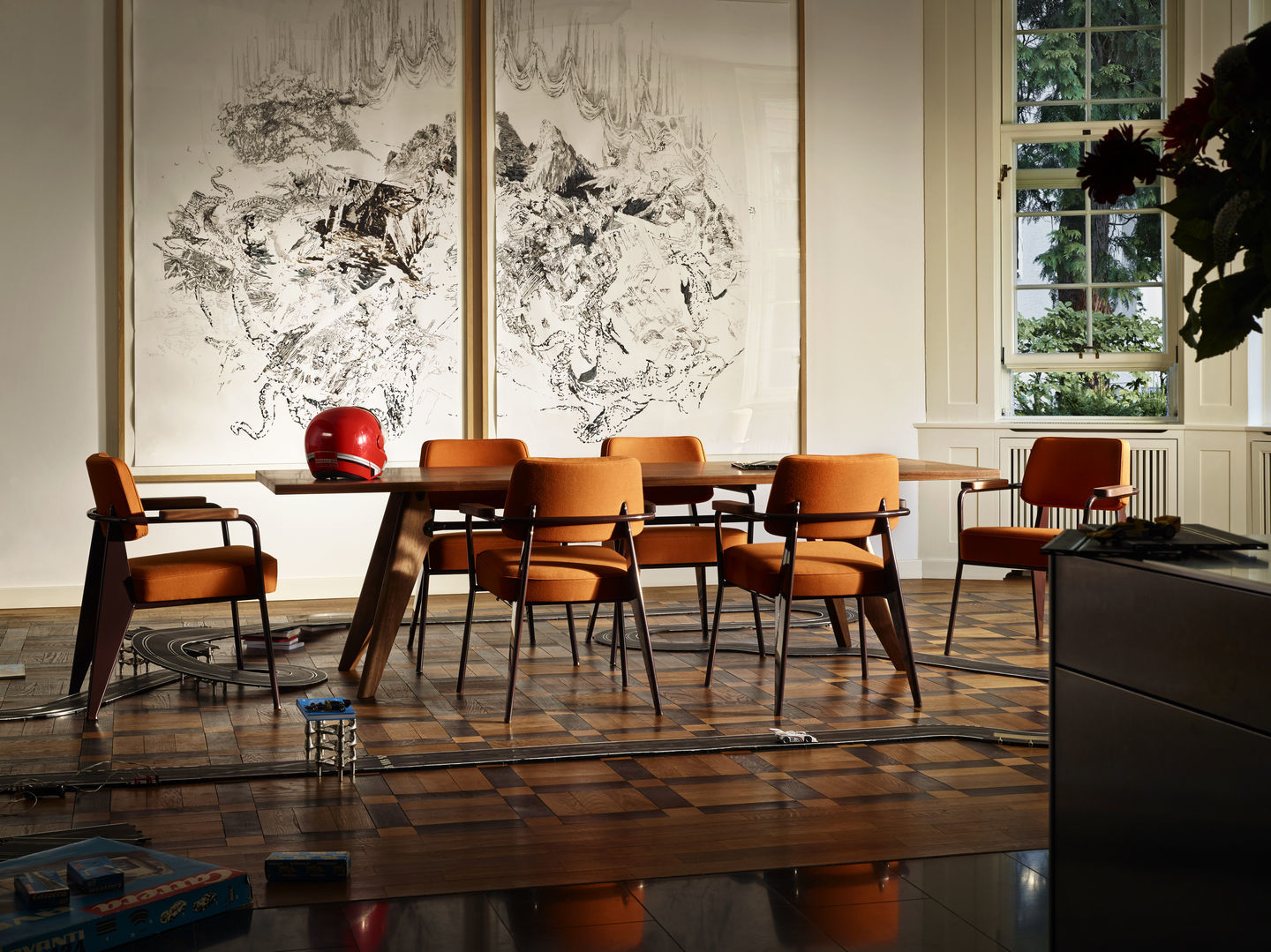 Oranger Fauteuil Direction Sessel von Vitra am Esstisch in modernem Wohnzimmer mit Kunstwerken.