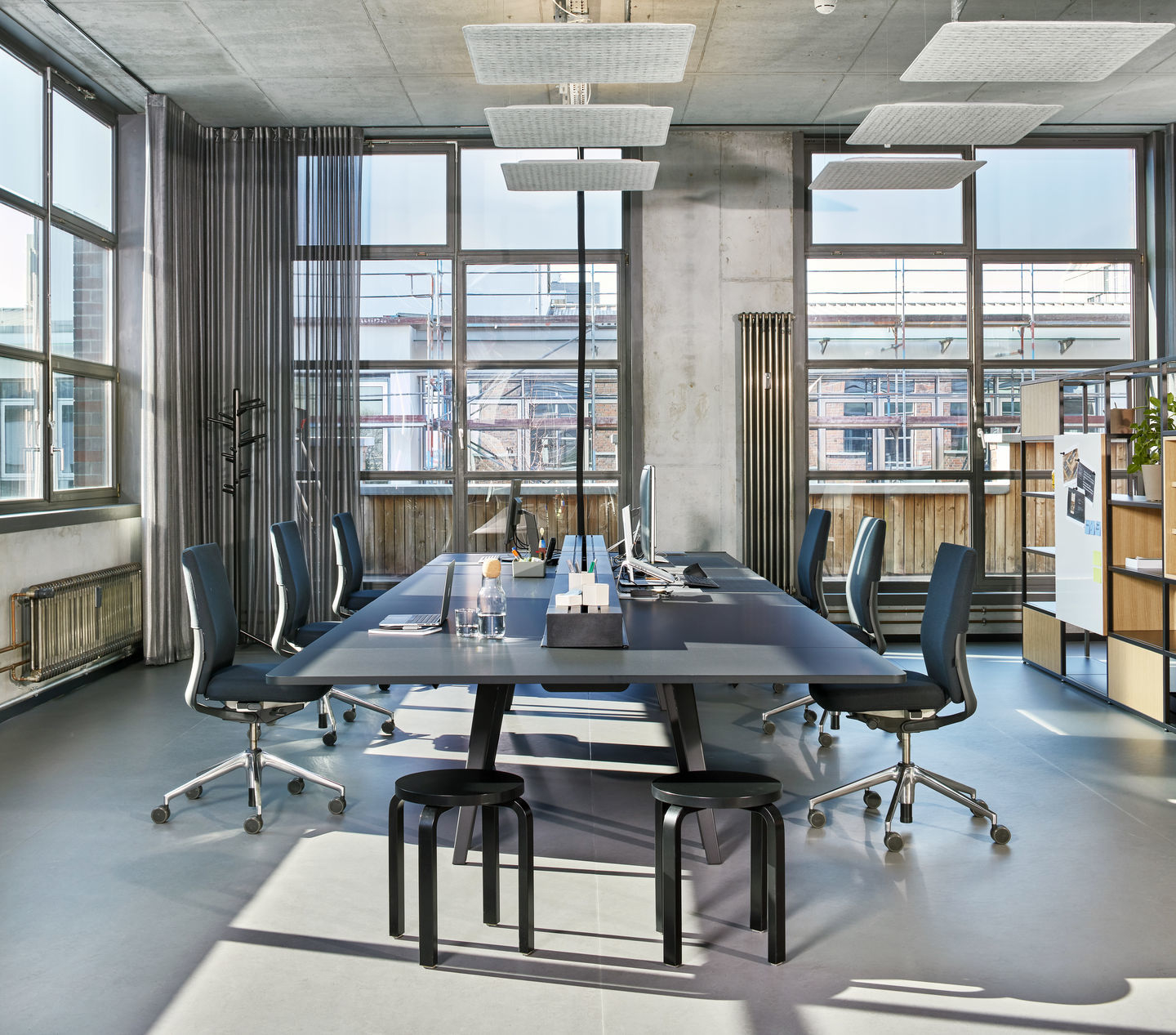 Büroraum mit langem Tisch und mehreren Vitra ID Chair Bürodrehstühlen in Grau.