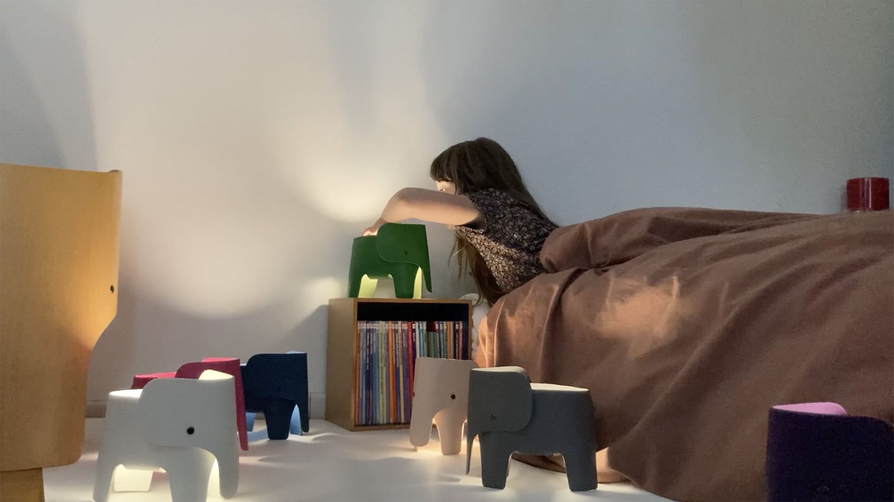 Mädchen schaltet grüne Elephant Akkuleuchte von EO Denmark auf Nachttisch ein.