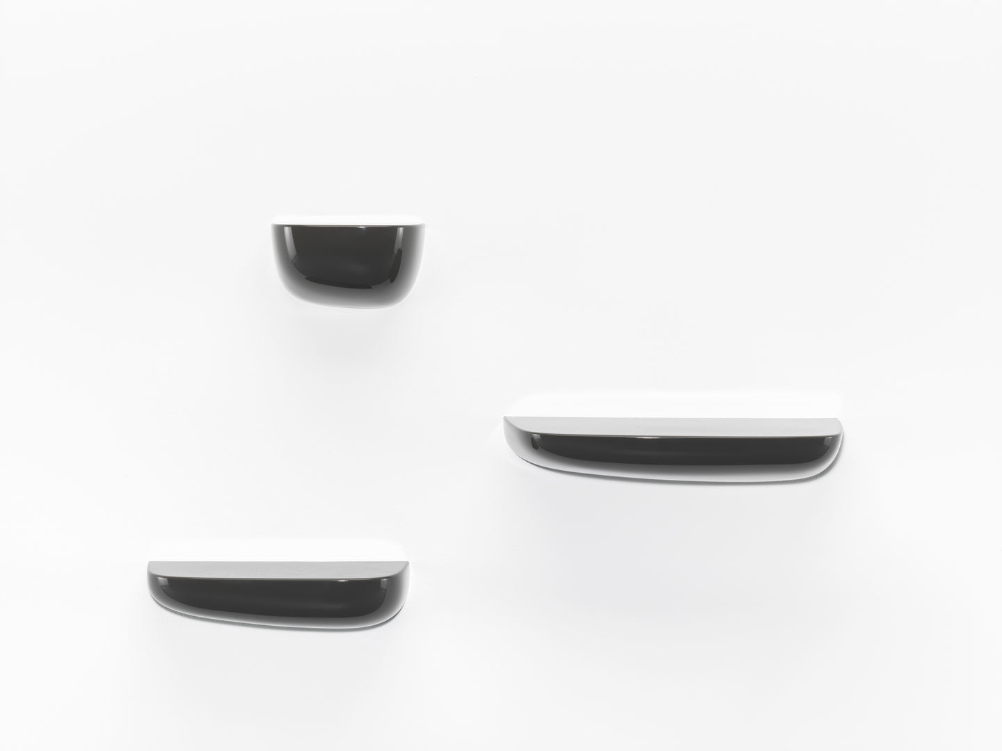 Drei schwarze Vitra Corniches Wandboards in verschiedenen Größen an einer weißen Wand.